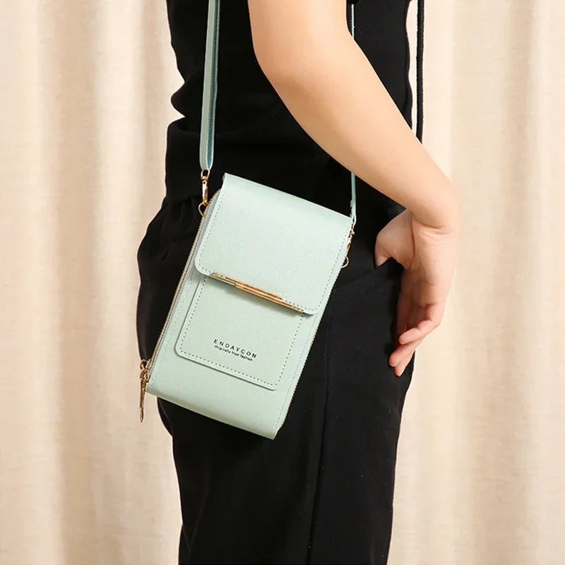 A light mint green luxury women's crossbody shoulder bag with gold hardware being held in a person's hand.