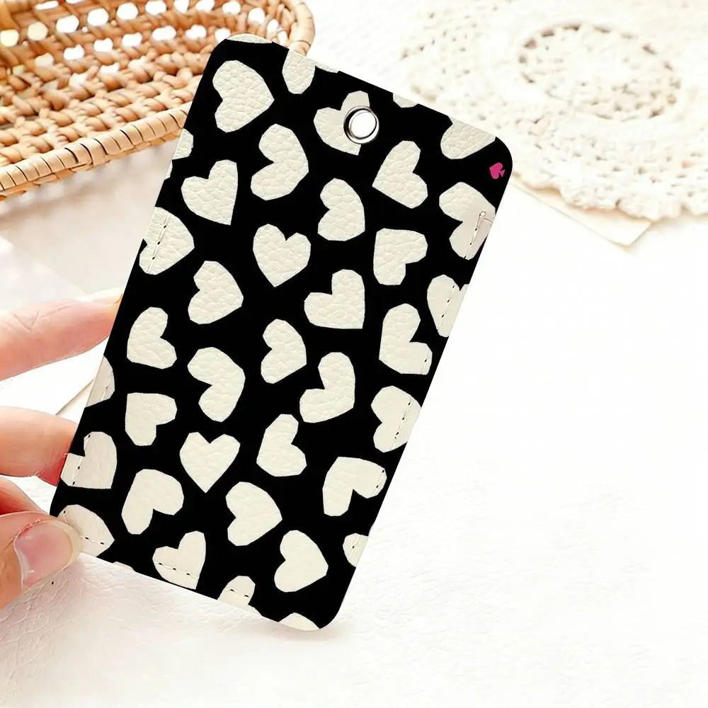 A black card holder featuring a pattern of white heart shapes, resting on a white surface next to a woven basket.