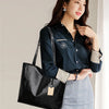 A woman models an elegant metallic zipper tote bag with a collared shirt and patterned skirt.