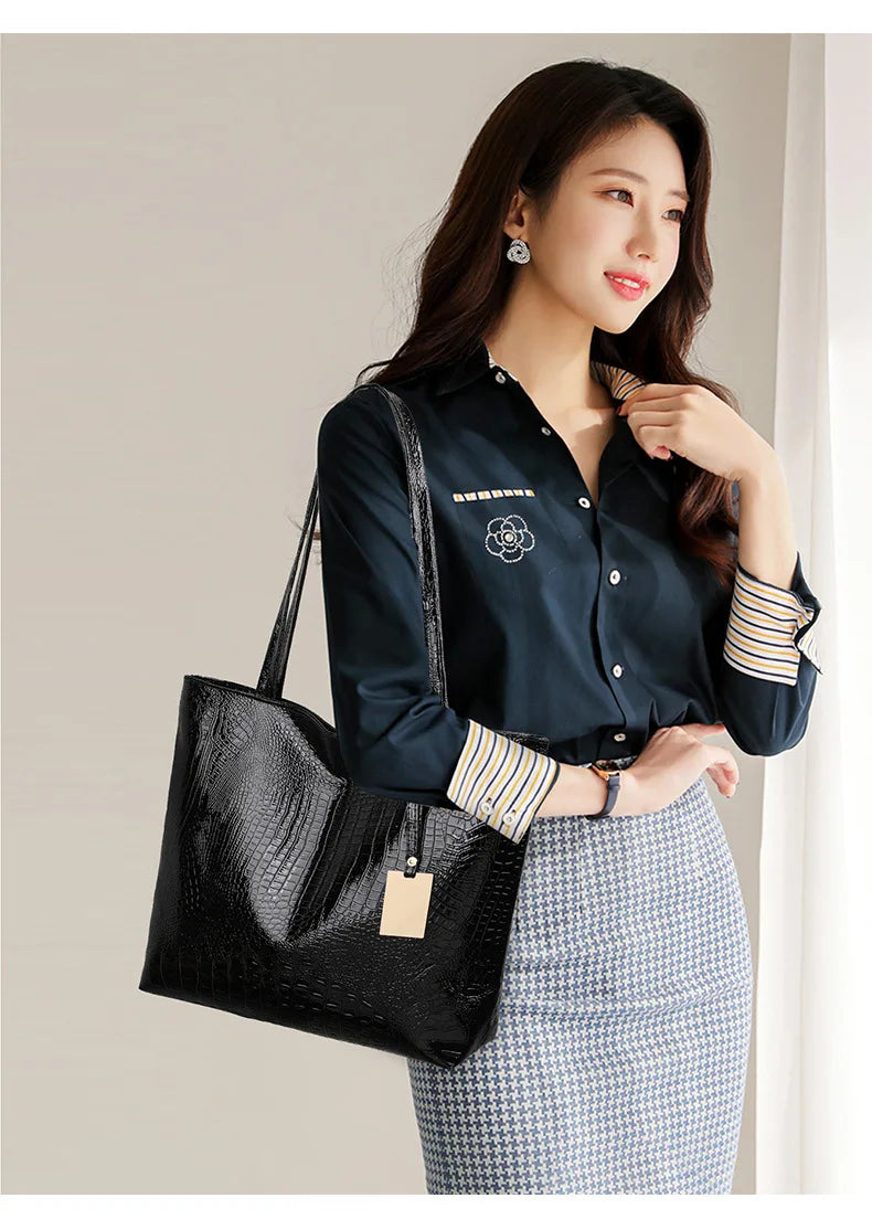 A woman models an elegant metallic zipper tote bag with a collared shirt and patterned skirt.