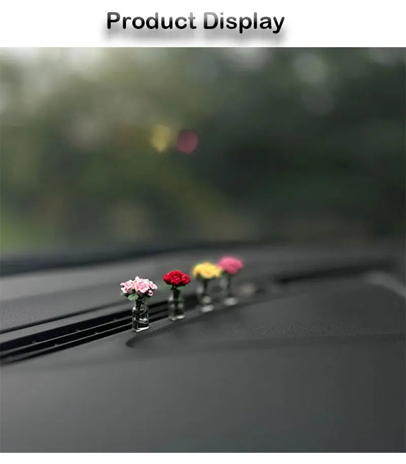 Anordnung kleiner, farbenfroher Mini-Rosen und Sonnenblumen auf einer dunklen Auto-Innenausstattung.
