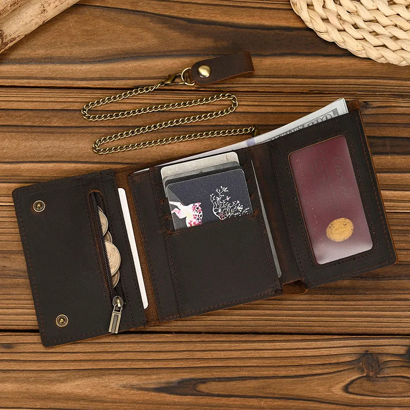 A dark brown genuine leather trifold wallet with a detachable gold chain is shown open on a wooden surface.