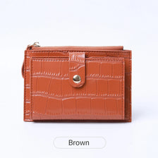 A brown mini crocodile pattern leather card holder with a zipper closure.