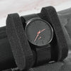 A black leather watch organizer travel case holding a rose gold analog watch.