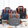 Une pile de trois sacs isothermes pour pique-nique bleu foncé, noir et gris avec des bretelles orange sur une surface blanche