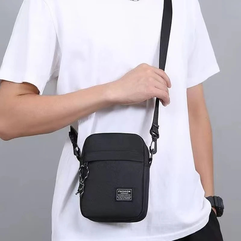 A man wearing a white t-shirt holds a black minimalist nylon crossbody bag.