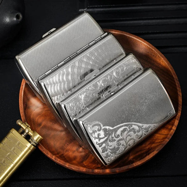 A silver metal cigarette case with an ornate design is displayed on a wooden plate.