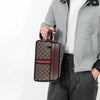 A brown leather clutch bag with a checkered pattern and striped accents is held by a person wearing a gray jacket.
