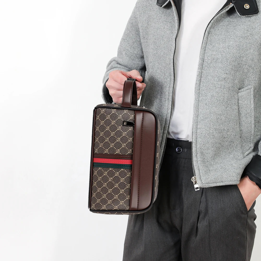 A brown leather clutch bag with a checkered pattern and striped accents is held by a person wearing a gray jacket.