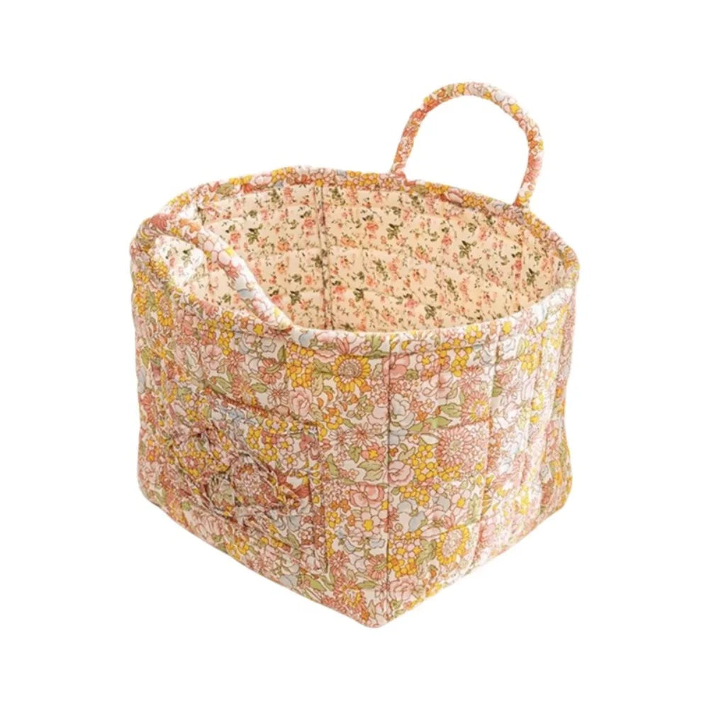 A quilted fabric storage basket with carry handles featuring a floral pattern in shades of pink and yellow.