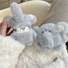 A light gray plush elephant case designed to hold AirPods is being held next to a white fluffy item.