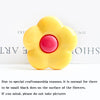 A yellow flower-shaped phone grip ring stand with small black dots on the surface.