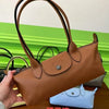 A brown leather shoulder bag with black straps is shown next to a light blue clutch.