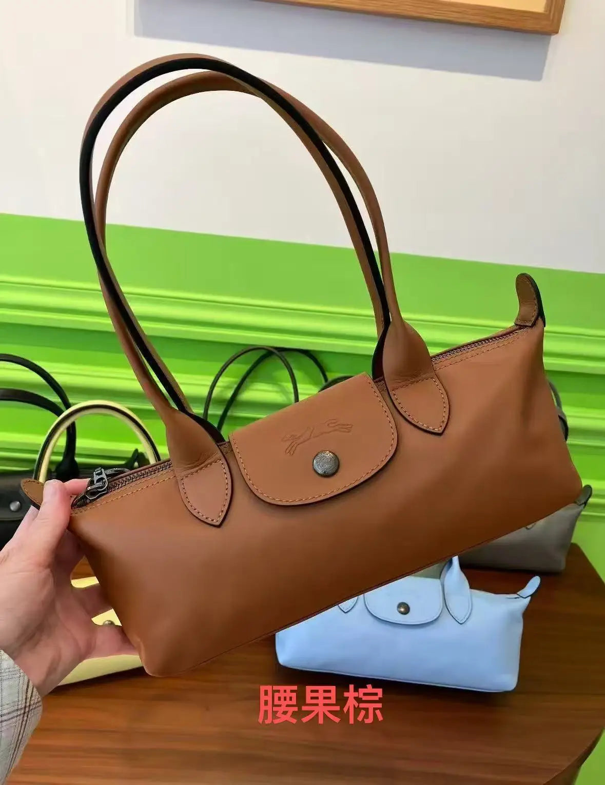 A brown leather shoulder bag with black straps is shown next to a light blue clutch.