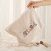 A beige corduroy makeup storage pouch with a pattern of small animal figures is being held by a hand.