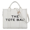 Sac cabas de luxe blanc de designer avec texte noir indiquant 'THE TOTE BAG'