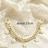 A gold chain necklace featuring bag flower pearl charms displayed on a white lace fabric.