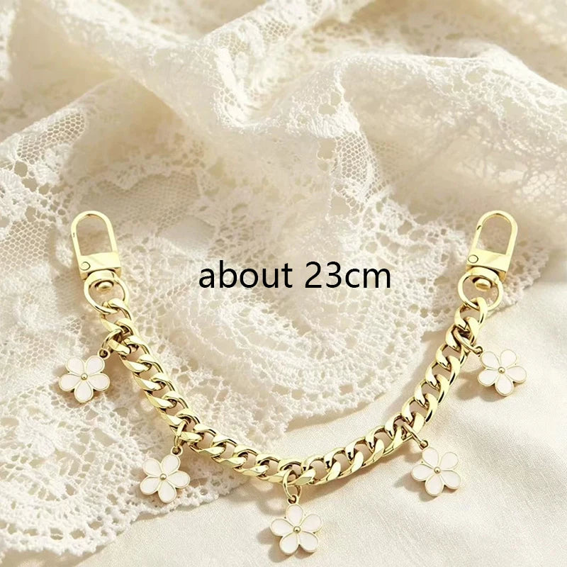 A gold chain necklace featuring bag flower pearl charms displayed on a white lace fabric.