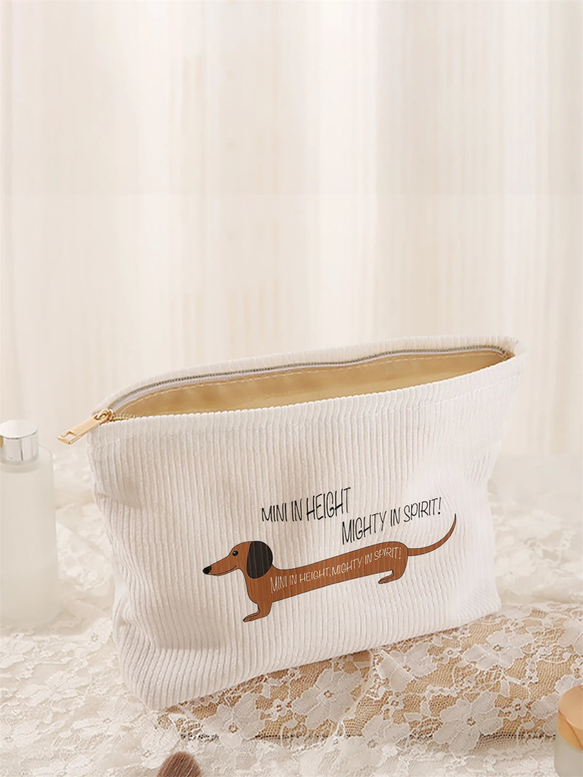 White corduroy makeup storage bag featuring a dachshund pattern resting on lace fabric.