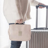 Eine hellrosa tragbare Reiseapotheke-Organizertasche wird von einer Person neben einem Koffer gehalten.
