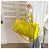 A bright yellow crocodile grain PU leather travel duffle bag carried by a person wearing a white sweater.
