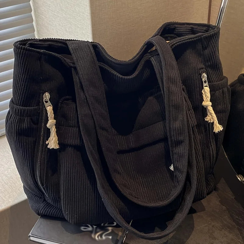 Sac fourre-tout noir en velours côtelé avec plusieurs poches, vue verticale.