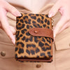 A close-up of a brown vintage leopard print women's wallet being held by hands against a beige blazer.