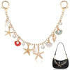 A delicate gold chain featuring starfish and pearl charms attached to a black leather bag.