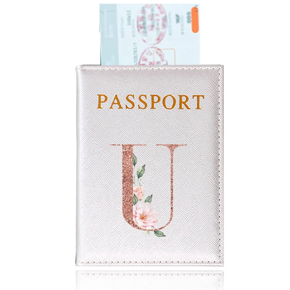 A pink leather passport holder featuring a gold initial U and a delicate floral design.