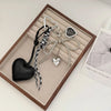 A set of black leather and silver bow keychains displayed in a wooden box.