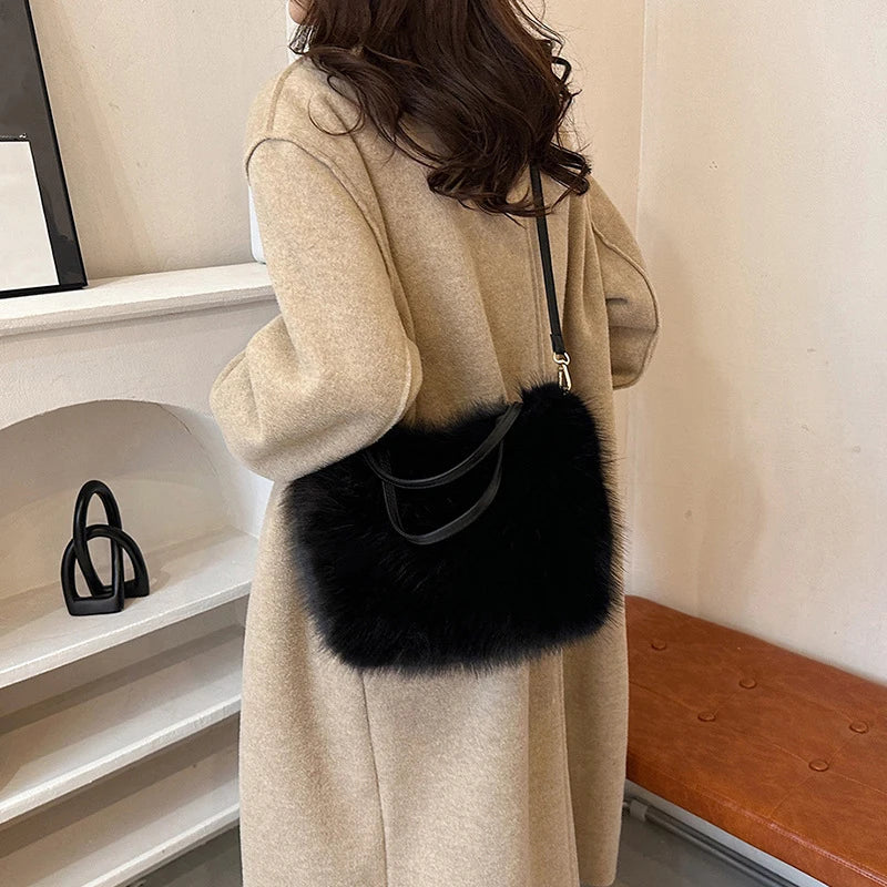 A woman is holding a beige coat and a black faux fur tote bag with a thin strap.