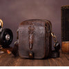 A dark brown genuine cow leather crossbody bag for men resting on a wooden surface.