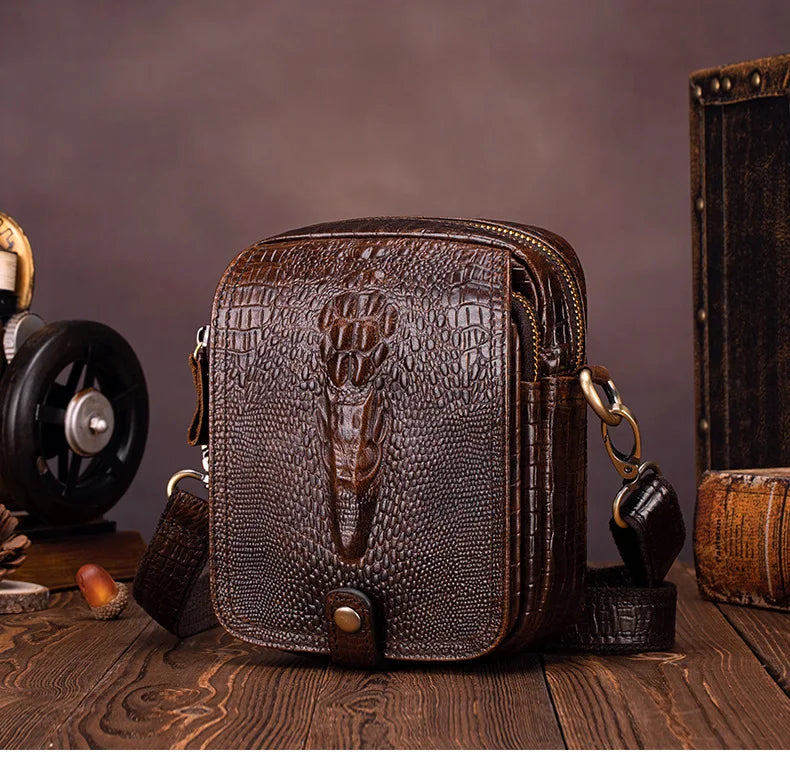 A dark brown genuine cow leather crossbody bag for men resting on a wooden surface.