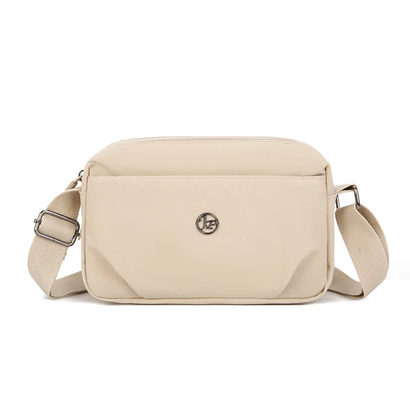 Bolso cruz impermeable beige de nylon con cierre de solapa y ribete de cuero.