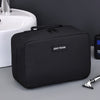 A black portable waterproof travel toiletry bag resting on a gray surface next to a white sink.