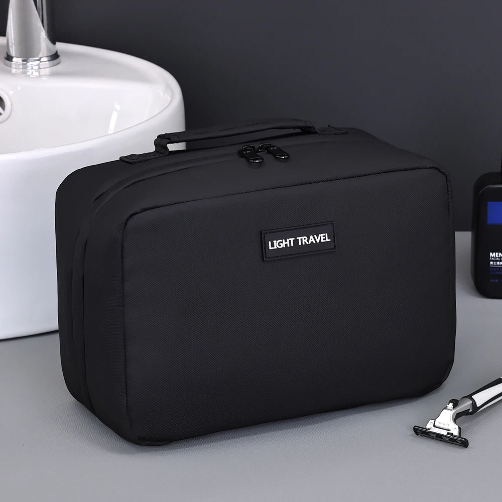 A black portable waterproof travel toiletry bag resting on a gray surface next to a white sink.