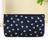 Black cosmetic bag with a white heart pattern and a silver zipper on a white surface.