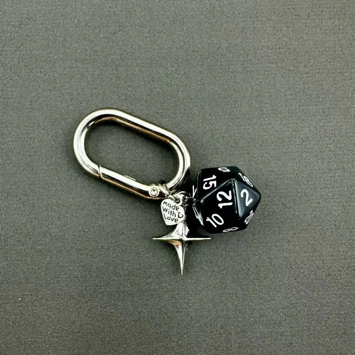 A silver-toned keychain featuring a black and white dice charm with a star pendant.