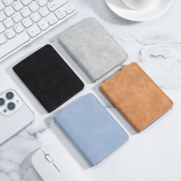 A collection of leather and fabric card wallets in black, gray, and tan colors arranged on a white marble surface.