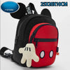 Una mochila negra con un bolsillo delantero rojo y un juguete de peluche blanco.