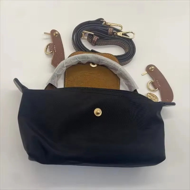 A black waterproof nylon crossbody bag with a tan leather strap and a detachable mini pouch.