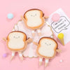A plush toy shaped like toast bread with a smiling face is shown next to a pink coin purse and a pink round object.
