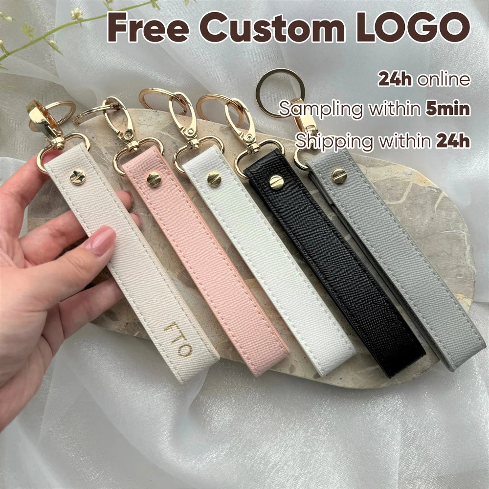 A hand holds several custom leather wristlet keychains in various colors and styles on a light background.