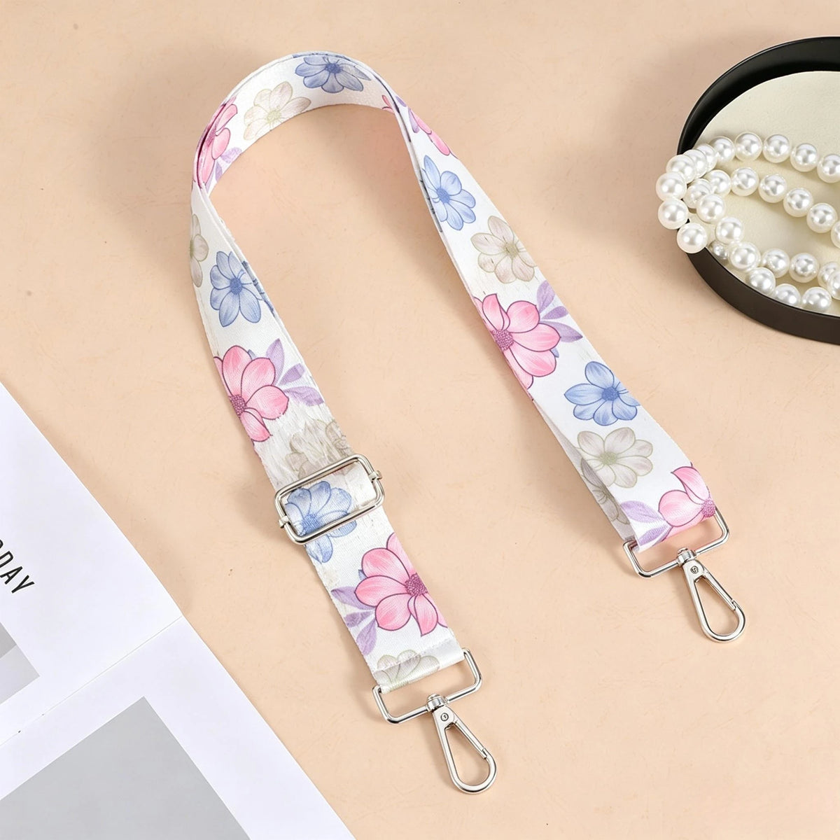 A floral patterned nylon crossbody bag strap with a silver metal buckle is displayed on a light background.