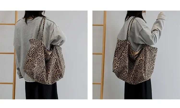 A person is holding a leopard print canvas crossbody tote bag against a light gray shirt.