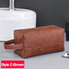 A brown PU leather toiletry bag resting on a gray surface next to a white ceramic sink.