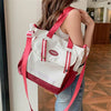 Eine Frau hält eine weiße und rosa Nylon-Tasche mit roten Riemen in einem informellen Innenraum.
