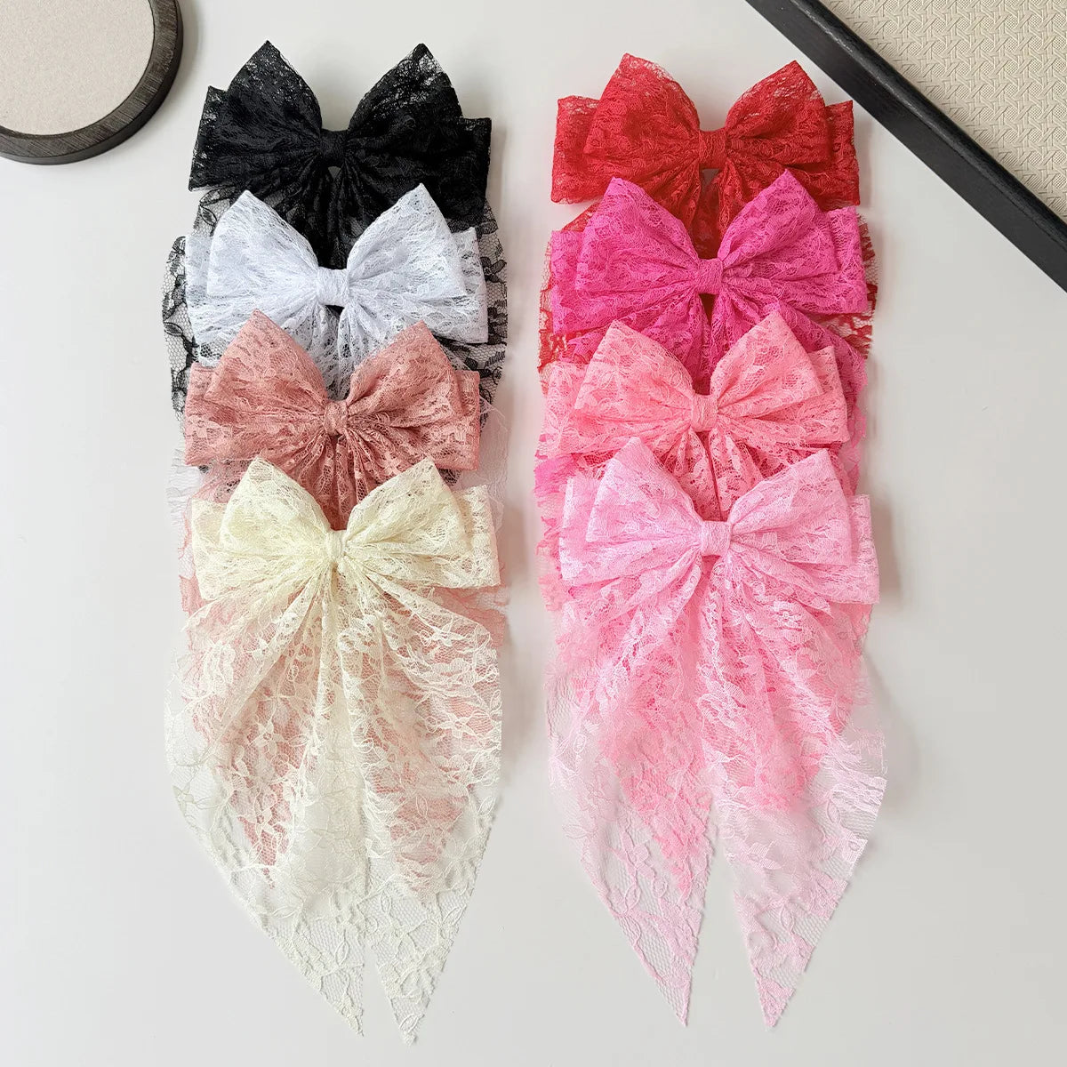 Eine Sammlung farbenfroher Spitzenbänder in schwarz, grau, weiß, rosa und rot, vertikal angeordnet.