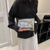 A woman holds a silver crocodile pattern coin purse clutch against a black shirt and white skirt.