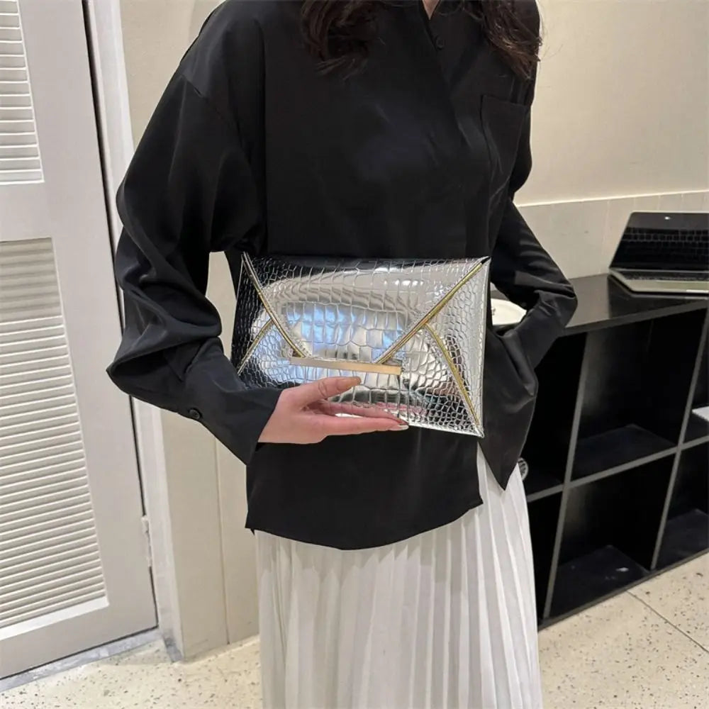 A woman holds a silver crocodile pattern coin purse clutch against a black shirt and white skirt.